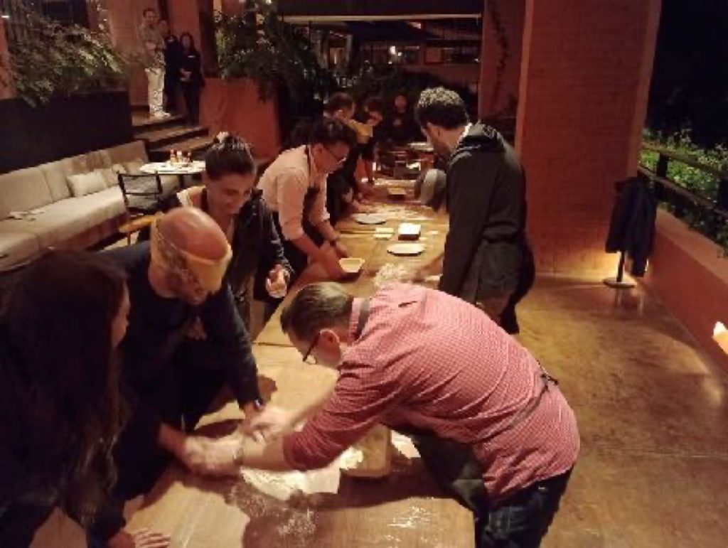 Participantes amasando en equipo durante la dinámica de pizzas ciegas